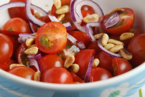 Simple salad of cherry tomatoes, red onion and toasted pine nuts